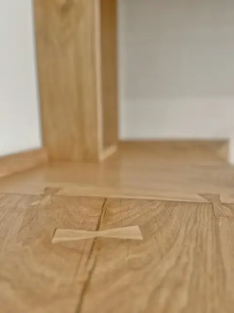 Close view of a butterfly key set across the joint between two oak boards.