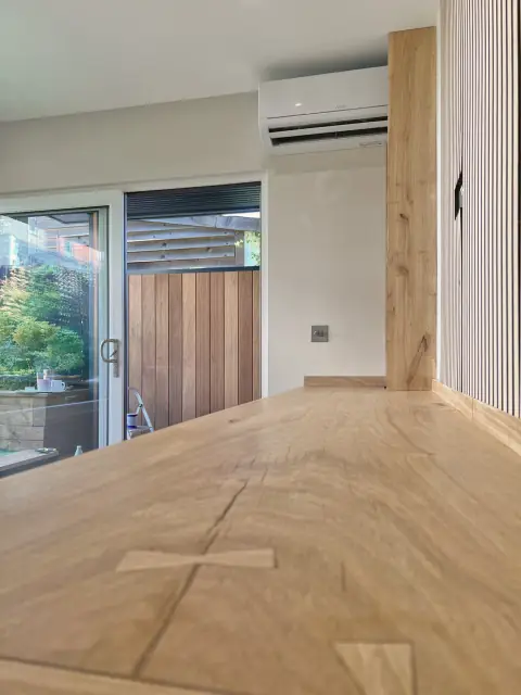 A long oak worktop whose boards are joined with contrasting butterfly keys, beside an oak post.